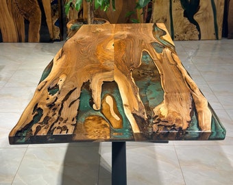 May include: A large wooden table with a live edge and green epoxy resin inlay. The table has a black metal base and is sitting on a tiled floor.