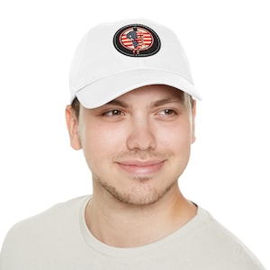 May include: White baseball cap with a circular patch showing a hockey player silhouette, an American flag design, and a black border. The cap is made of a soft material and has a curved peak.