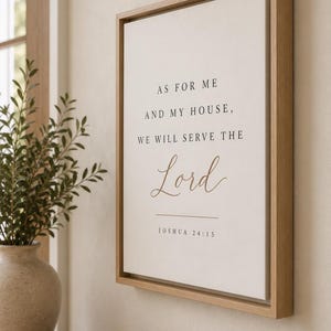 May include: A rectangular wall sign in a light wood frame featuring a white background with black and brown text that reads: AS FOR ME AND MY HOUSE, WE WILL SERVE THE Lord JOSHUA 24:15. The sign is mounted on a wall, displaying a religious quote.