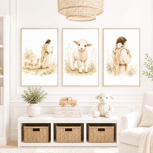 Könnte beinhalten: Ein Set aus drei gerahmten Wandkunstdrucken mit Aquarellillustrationen. Der linke Druck zeigt eine Figur mit Stab, die mit Schafen geht, der mittlere Druck zeigt ein einzelnes Lamm und der rechte Druck zeigt eine Figur, die ein Lamm trägt.