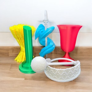 May include: A collection of colorful, abstract 3D-printed objects. Includes a yellow, fan-shaped item, a green cylinder, a blue swirled sculpture, a red tulip-shaped vase, and a white decorative band with a ball.
