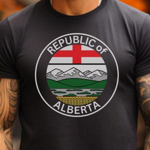 May include: A black t-shirt with a white circle graphic featuring the text "Republic of Alberta" and a stylized image of mountains, a river, and a red cross.