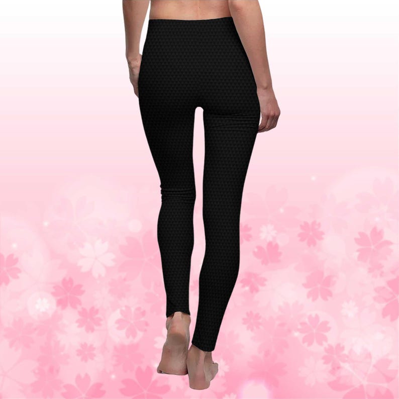 May include: Black leggings with a textured pattern. The leggings are form-fitting and reach the ankles. The background is a soft pink with a floral design.