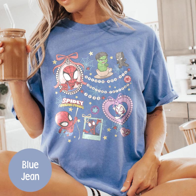 Puede incluir: Camiseta azul vaquera con Spidey y sus Incre&iacute;bles Amigos. La camiseta presenta gr&aacute;ficos coloridos de Spider-Man, Hulk, Pantera Negra y Spider-Gwen. Tambi&eacute;n es visible el texto "Spidey Amazing Friends".