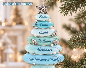 May include: A Christmas tree-shaped ornament made of stacked, smooth, light blue stones. The ornament features a silver starfish topper, small silver anchor and seashell charms, and white beads. It is inscribed with the names Sam, Liam, David, William, Alexander, The Thompson Family, and the year 2026.