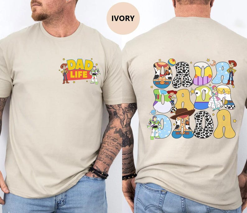 May include: A beige t-shirt with a graphic of Toy Story characters spelling out "DAD DAD DAD" on the back. The front of the shirt has a graphic of Woody and Buzz Lightyear with the text "DAD LIFE".