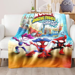 K&ouml;nnte beinhalten: Eine farbenfrohe Decke mit Figuren aus "Robert Amazing Friends Water Webs". Das Design umfasst Cartoonfiguren, ein Piratenschiff und das Meer. Die Decke ist &uuml;ber ein wei&szlig;es Sofa drapiert.