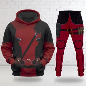 May include: A red and black hooded sweatshirt and matching trousers set featuring a graphic print of a tactical suit with a utility belt, shoulder strap, holster, and ammunition pouches, designed with a hood and long sleeves on the sweatshirt.