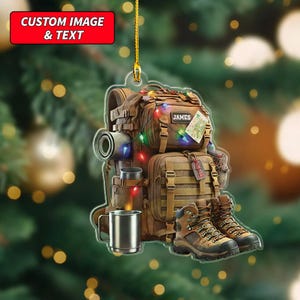 May include: A brown backpack Christmas ornament with hiking boots, a rolled-up sleeping pad, and a metal mug. The ornament has a map and the name "JAMES" on it. The top of the ornament has the text "CUSTOM IMAGE & TEXT".