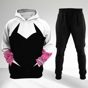 May include: A two-piece outfit featuring a hooded sweatshirt and matching pants. The sweatshirt is white and black with pink accents, and the pants are solid black. The design is a graphic representation of a superhero costume.
