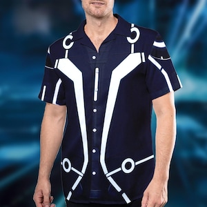 May include: Navy blue button-down shirt with a white geometric design. The short-sleeved shirt features a camp collar and a series of white lines and shapes that create a futuristic aesthetic. The shirt has a classic button-up front.