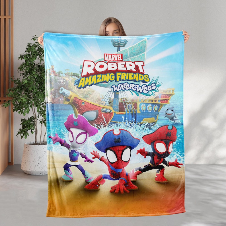 K&ouml;nnte beinhalten: Eine Marvel "Robert Amazing Friends Water Webs" Decke mit Cartoon-Spider-Man-Charakteren in Piratenh&uuml;ten. Die Decke hat einen blauen Ozean- und Himmelhintergrund mit einem Piratenschiff und einem Hai.