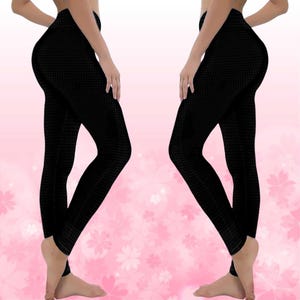 May include: Black leggings with a textured pattern. The leggings are form-fitting and reach the ankles. The background is a soft pink with white flower shapes.