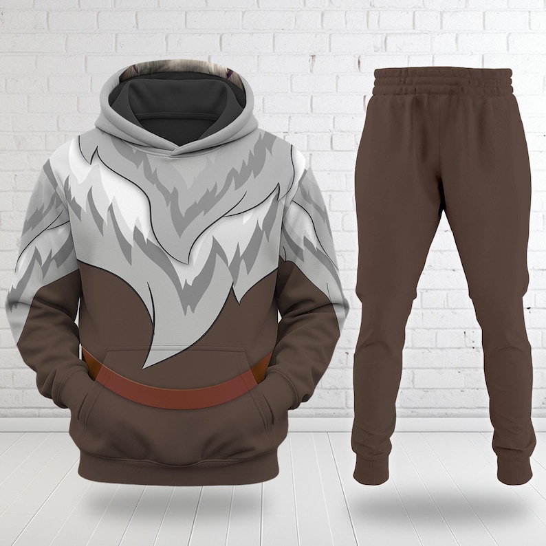 May include: A two-piece brown and white outfit featuring a hooded sweatshirt and matching sweatpants. The sweatshirt has a brown base with a white and gray fur-like design across the chest and shoulders. The sweatpants are solid brown.