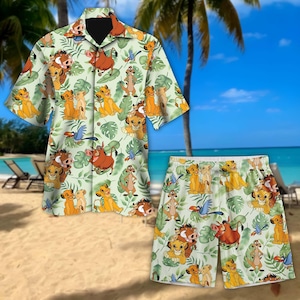 May include: A green and white button-up shirt and matching shorts with a tropical print featuring characters from the Lion King movie. The print includes Simba, Nala, Timon, Pumbaa, and Zazu.