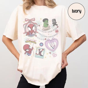 Puede incluir: Camiseta de color marfil con gr&aacute;ficos de dibujos animados coloridos de Spider-Man y otros personajes de Marvel. El dise&ntilde;o incluye el texto "Spidey and His Amazing Friends" y otros elementos decorativos. La camiseta tiene mangas cortas y un corte holgado.