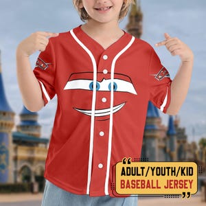 Pu&ograve; includere: Maglia da baseball rossa con finiture bianche e un disegno a forma di volto di auto dei cartoni animati. La maglia ha una chiusura a bottoni sul davanti e maniche corte. Il testo sull'immagine recita "ADULT/YOUTH/KID BASEBALL JERSEY".