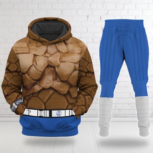 May include: A brown and blue hoodie and trousers set. The hoodie has a textured, rocky pattern, a blue waistband with a white belt and the number 4. The blue trousers have white cuffs and vertical lines.