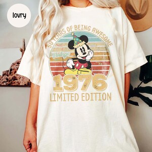 Puede incluir: Camiseta color crema con un dise&ntilde;o vintage de Mickey Mouse celebrando su 50 aniversario. El gr&aacute;fico incluye el texto "50 Years of Being Awesome" y "1976 Limited Edition" en un estilo retro.