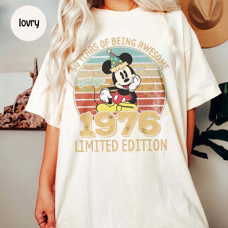 Puede incluir: Camiseta color crema con un dise&ntilde;o vintage de Mickey Mouse celebrando su 50 aniversario. El gr&aacute;fico incluye el texto "50 Years of Being Awesome" y "1976 Limited Edition" en un estilo retro.