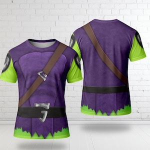 K&ouml;nnte beinhalten: Ein lila T-Shirt mit Kost&uuml;mdesign, mit einem braunen Riemen, einem schwarzen G&uuml;rtel und gr&uuml;nen Akzenten an den &Auml;rmeln und am unteren Saum. Das Design &auml;hnelt einem mittelalterlichen oder Fantasy-Outfit.