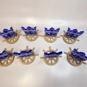 Peut inclure: Huit troph&eacute;es en forme de couronne bleu et blanc avec le texte "17/01/2023" sur chacun, mont&eacute;s sur des socles de roue de navire dor&eacute;s.
