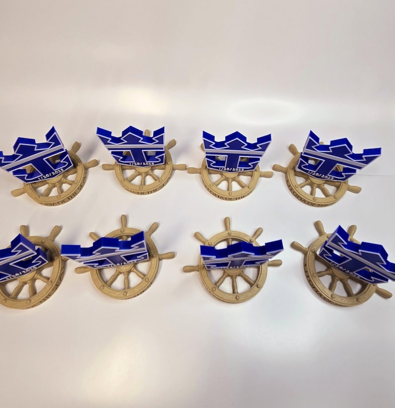 Peut inclure: Huit troph&eacute;es en forme de couronne bleu et blanc avec le texte "17/01/2023" sur chacun, mont&eacute;s sur des socles de roue de navire dor&eacute;s.