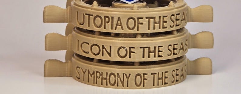 Peut inclure: Trois sous-verres en bois brun empil&eacute;s avec les noms des navires de croisi&egrave;re Royal Caribbean : Utopia of the Seas, Icon of the Seas et Symphony of the Seas.
