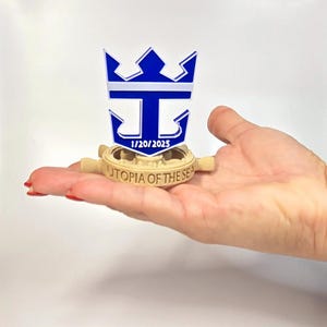 Peut inclure: Mod&egrave;le imprim&eacute; en 3D d'un gouvernail de navire de croisi&egrave;re avec le logo de Royal Caribbean International et le texte "Utopia of the Seas" ainsi que la date "1/20/2025".