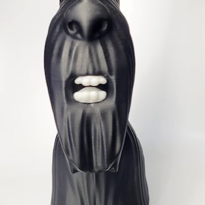 May include: A black sculpture of a Scottish Terrier dog with white teeth and eyes. The dog has a long, textured snout and pointed ears. The sculpture is set against a white background.