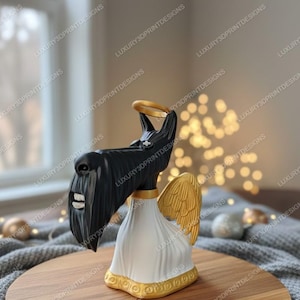 May include: A black and white figurine of a Scottish Terrier dog with angel wings and a halo. The dog is wearing a white robe with gold trim. The text "LUXURY3DPRINTDESIGNS" is visible on the background.
