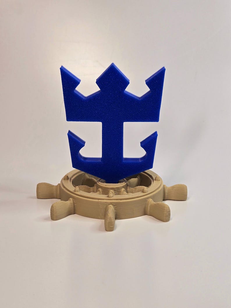 Peut inclure: Un logo Royal Caribbean International imprim&eacute; en 3D de couleur bleue avec une couronne et une ancre, mont&eacute; sur un volant de navire imprim&eacute; en 3D de couleur beige.