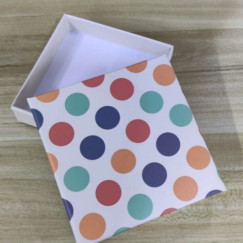 May include: A white gift box with a lid. The box is decorated with a polka dot pattern in shades of orange, red, blue, and green.