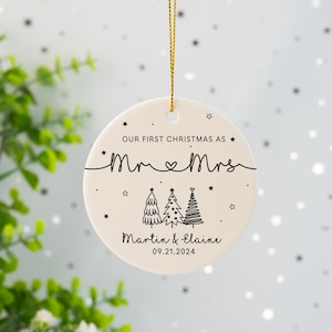 May include: White ceramic Christmas ornament with black text that reads "Our first Christmas as Mr. & Mrs. Martin & Elaine 09.21.2024". The ornament features three stylized Christmas trees with stars.