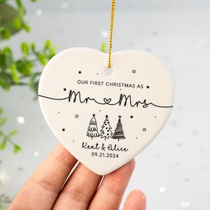 May include: White heart-shaped ceramic ornament with black text that reads "Our first Christmas as Mr & Mrs Kent & Alice 09.21.2024" and three stylized Christmas trees.