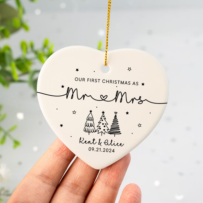 May include: White heart-shaped ceramic ornament with black text that reads "Our first Christmas as Mr & Mrs Kent & Alice 09.21.2024" and three stylized Christmas trees.