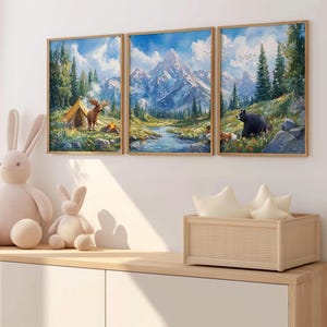 Könnte beinhalten: Drei gerahmte Aquarellbilder, die eine Berglandschaft mit einem Zelt, einem Reh, einem Bären und einem Fuchs zeigen. Die Bilder hängen an einer weißen Wand über einem Holzregal mit einem geflochtenen Korb.