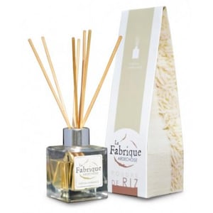 Puede incluir: Una botella de vidrio transparente con una tapa plateada y palitos de madera, llena de un líquido amarillo claro. La botella está etiquetada con "La Fabrique Ardèchoise" y "Poudre de Riz". La botella está sentada sobre una superficie blanca junto a una caja blanca con una etiqueta marrón que dice "La Fabrique Ardèchoise" y "Poudre de Riz".