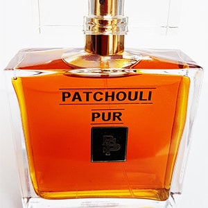 May include: A clear glass bottle of Patchouli Pur perfume with a gold cap. The bottle is filled with a dark amber liquid.