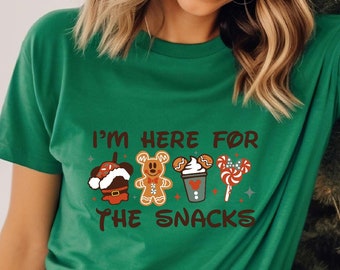 May include: Green t-shirt with a white graphic that says "I'm here for the snacks" and features a gingerbread man, a snowman, a cup of hot chocolate, and a candy cane.
