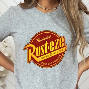 May include: A gray t-shirt with a red and yellow logo that says "Medicated Rust-eze Bumper Ointment Rear End Formula".