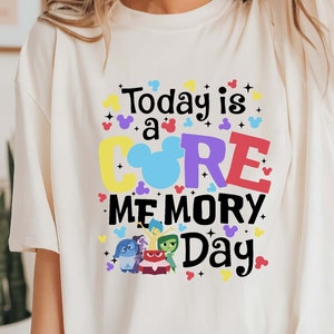 May include: White t-shirt with a colorful graphic that says "Today is a CORE MEMORY Day." The graphic features Mickey Mouse ears and characters from the movie Inside Out.