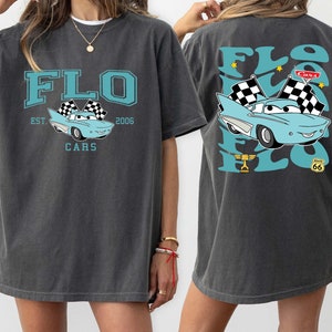 May include: A grey oversized t-shirt with a blue car graphic and the text "FLO EST 2006 CARS" on the front and the text "FLO" with a blue car graphic on the back.