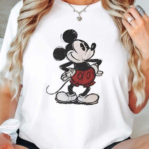 May include: White t-shirt with a black and white cartoon image of Mickey Mouse wearing red shorts.