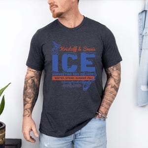 May include: Dark gray t-shirt with the text "Kristoff & Sven's ICE" in blue and orange. The shirt also includes the text "Harvesting and Delivery" and "Winter, Spring, Summer, Fall".