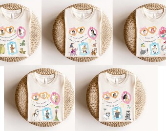 May include: Five white t-shirts with different Disney princess designs printed on them. Each shirt features a different princess with her animal companion and a banner with the princess's name. The shirts are displayed on a light brown woven surface.
