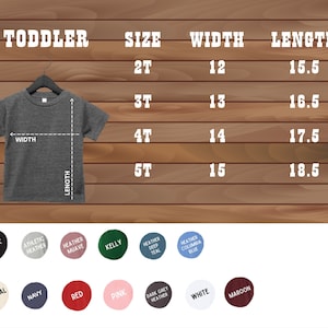 May include: A gray toddler t-shirt displayed on a hanger, with a size chart showing measurements in inches. The chart lists sizes 2T to 5T, with corresponding width and length measurements. Color options include black, athletic heather, and red.