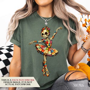 May include: A moss green t-shirt featuring a graphic of a skeleton ballerina made of colourful faux patchwork fabric. The skeleton has a button eye and wears a multi-coloured tutu. Text on the image states: This is a faux patchwork design.