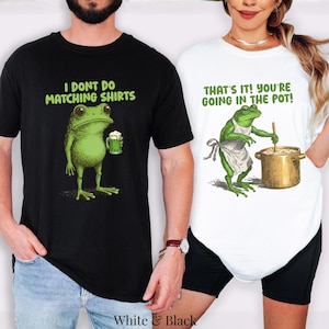 May include: A black t-shirt with a green frog holding a beer mug and the text I DONT DO MATCHING SHIRTS, and a white t-shirt with a green frog wearing an apron, stirring a pot, and the text THATS IT! YOURE GOING IN THE POT!