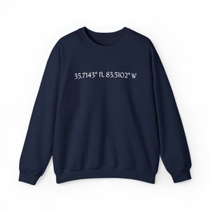 May include: A navy blue sweatshirt with white text that reads "35.7143° N, 83.5102° W".